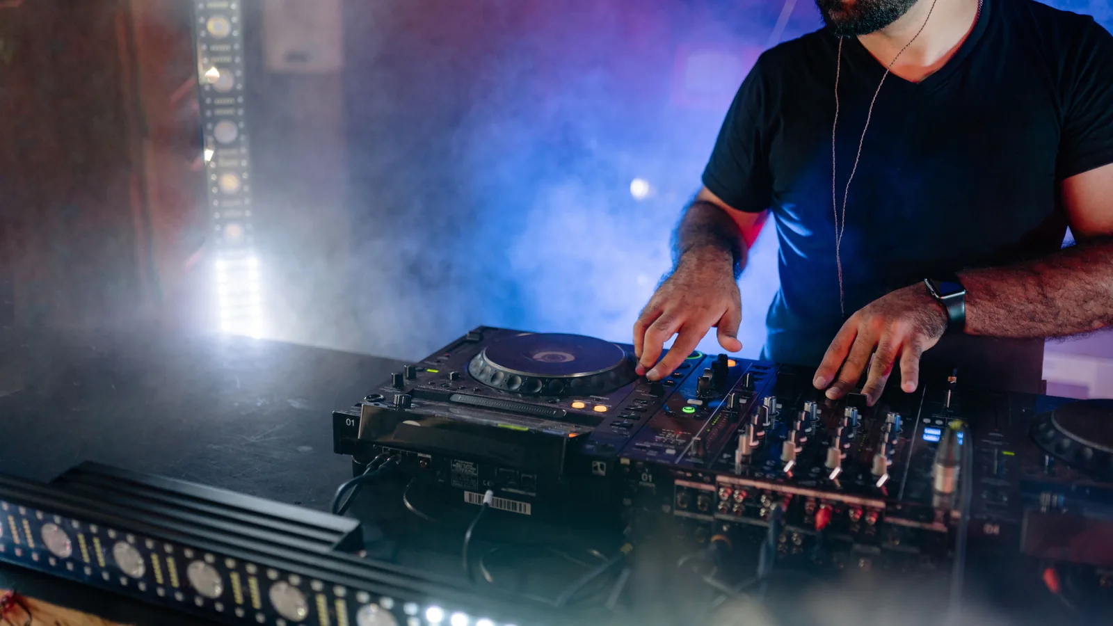 Clubbühne mit Nebel, farbigem Moving-Light und DJ-Setup